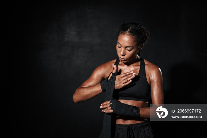 Image of african american woman in sportswear wearing boxing hand wraps