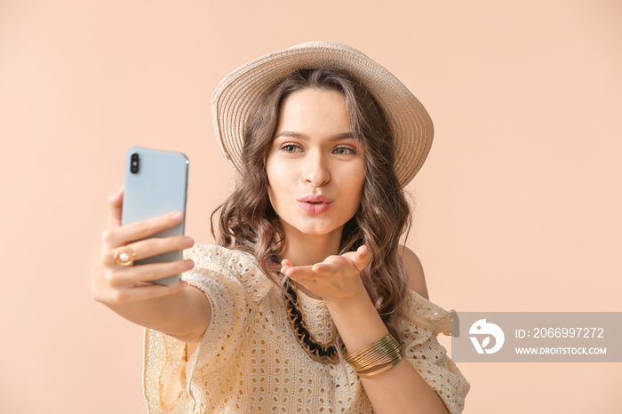 Young woman taking selfie on color background