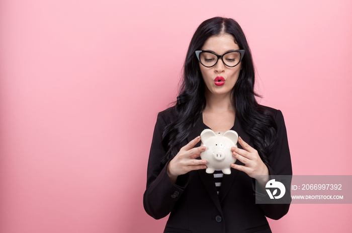 Young woman with a piggy bank on a pink background