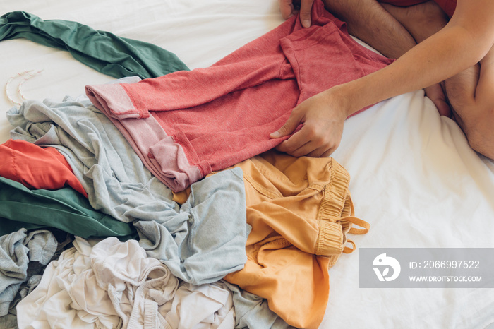 Man is folding and arranging the clothes on the bed.