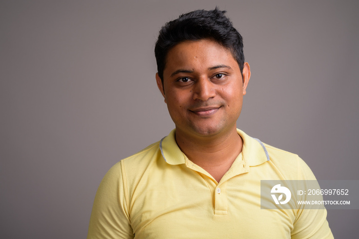 Portrait of young Indian man against gray background