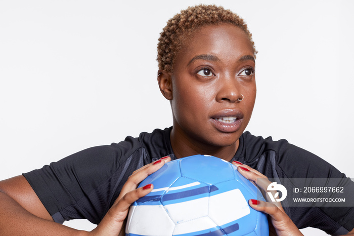 Studio portrait of female soccer player with ball