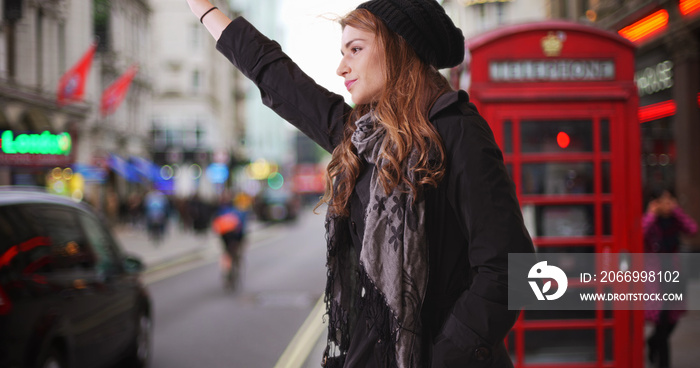 Attractive Caucasian female calling for taxi cab in London street