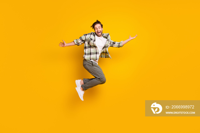 Full length photo of cheerful happy man jump up raise hands good mood smile isolated on yellow color background