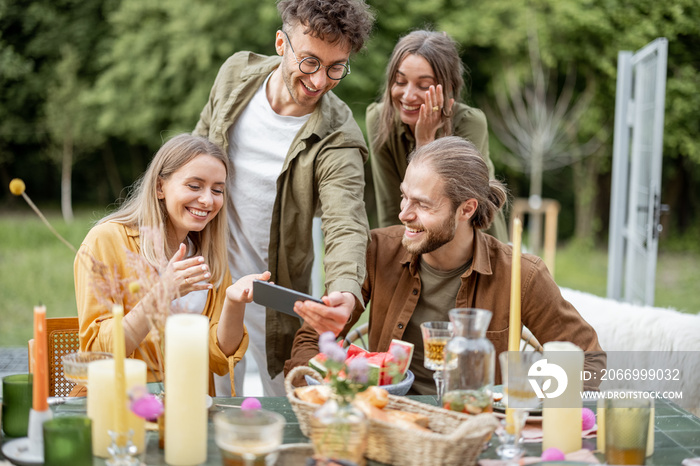 A group of young friends having great summertime, dining and talking at backyard of the country house in nature