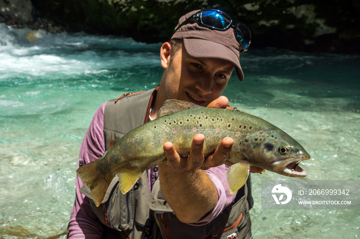 Fly fisherman holding brown trout