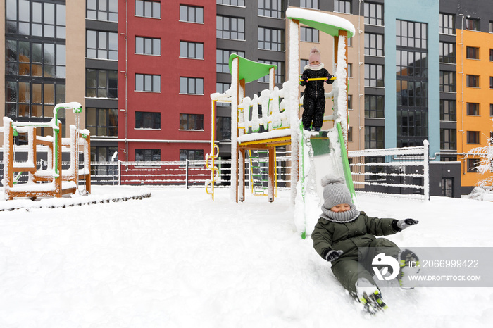 children ride on a swing in the yard in winter. snowy playground