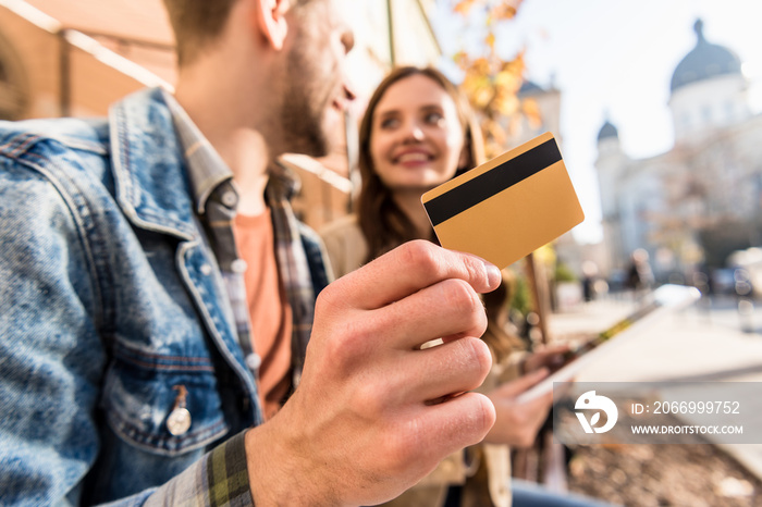 Cropped view of man with girl looking at each other, smiling and showing credit card