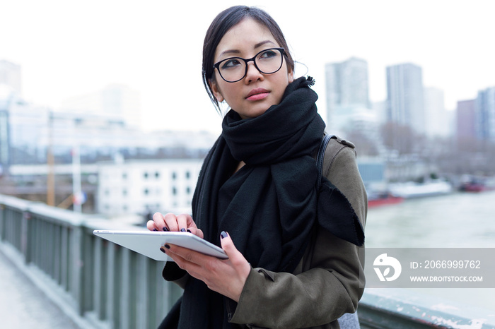 Beautiful asian young woman using her digital tablet in front of Seine river in Paris.