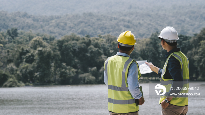 Two young maintenance engineer man working with blueprint on the mountain, Environmental engineering concept..