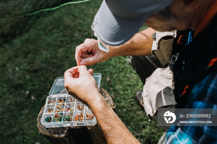 Close up shot of senior fisherman’s hands tying a fly for fishing. Fly fishing concept.