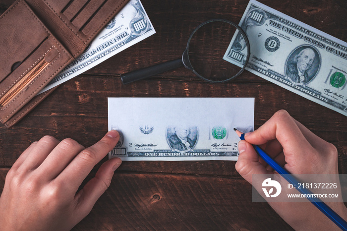 Counterfeiter forges banknotes. Fake concept. Fake money, a wallet with American dollars, a magnifier on a wooden background. Top view