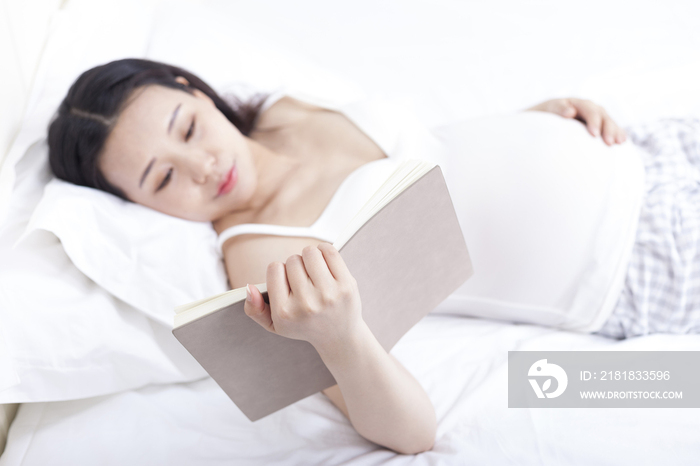 孕妇躺在床上看书