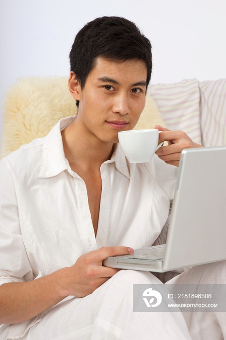 年轻男人边喝咖啡边看笔记本电脑