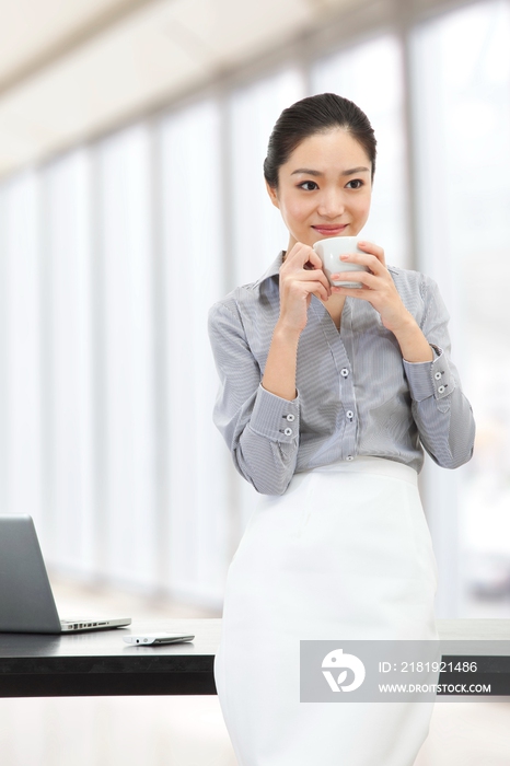 年轻商务女士端着咖啡杯