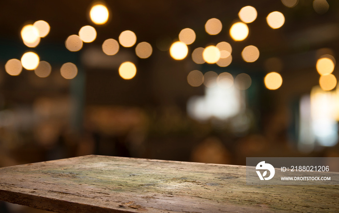 Empty wood table top on blur light gold bokeh of cafe restaurant in dark background