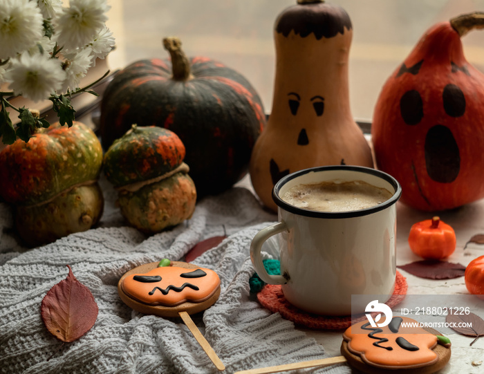 Happy Halloween concept. Fresh Halloween gingerbread cookies and a cup of hot coffee among pumpkins 