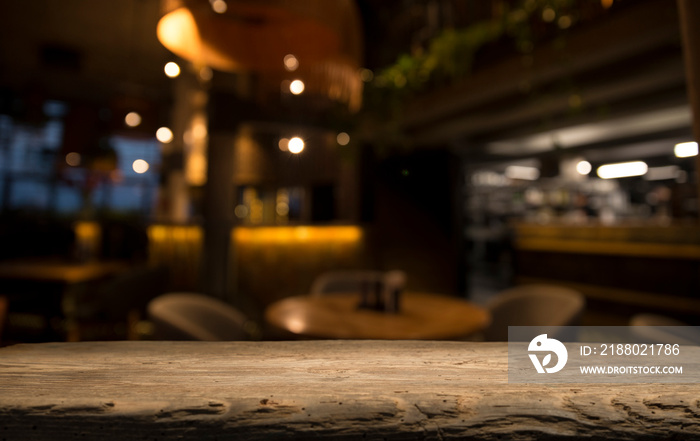 Empty wood table top on blur light gold bokeh of cafe restaurant in dark background