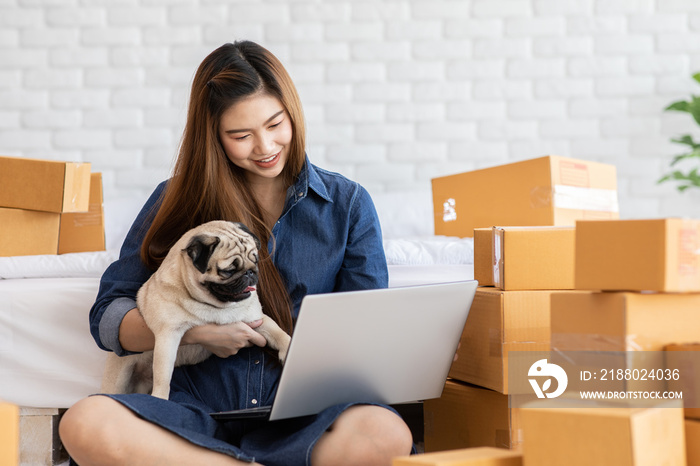SME entrepreneur of Young women working with laptop for Online shopping at home with her dog pug bre