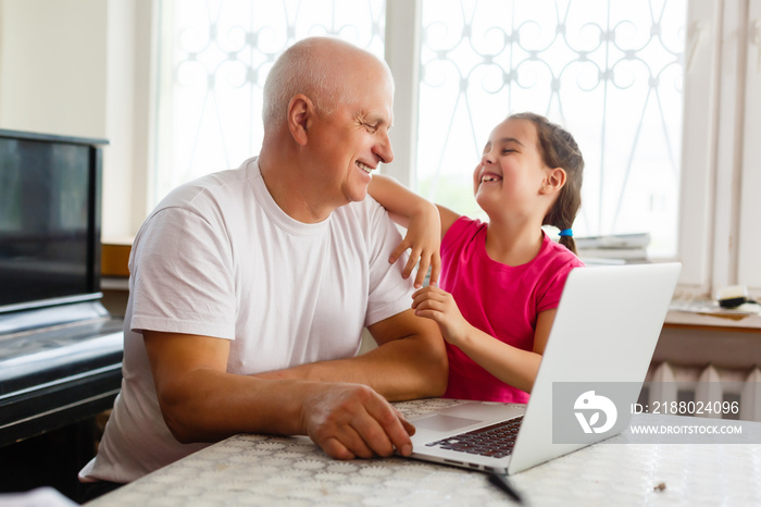 Grandfather and his granddaughter using a laptop together.