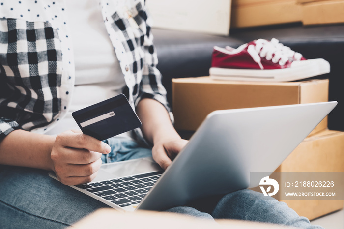 Young asian pretty girl using credit card and laptop computer for shopping online at home