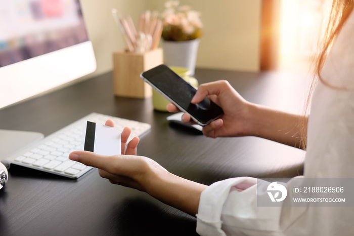 Woman shopping online with credit card and smartphone computer.