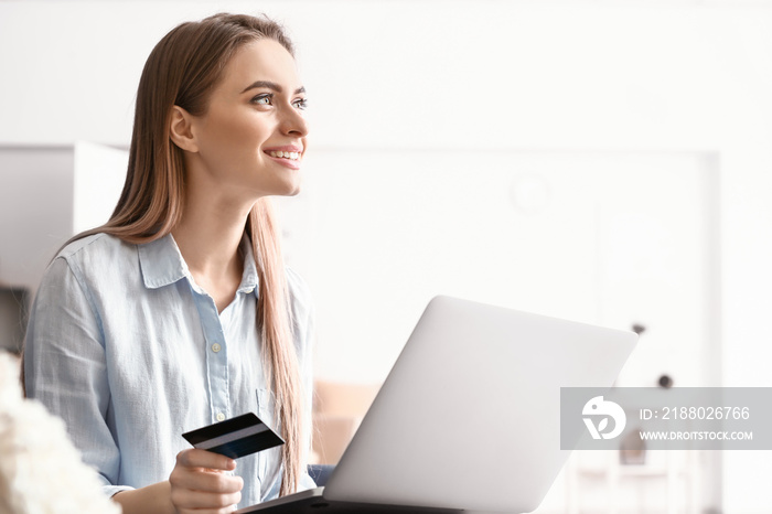 Young woman with credit card shopping online at home