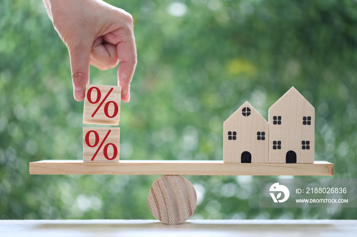 Interest rate up and Banking concept, Model house with Percentage symbol icon on wood scale seesaw o