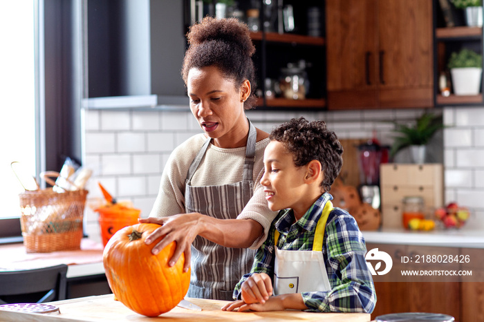 Mother with his son prepare pumpkin for halloween in the kitchen