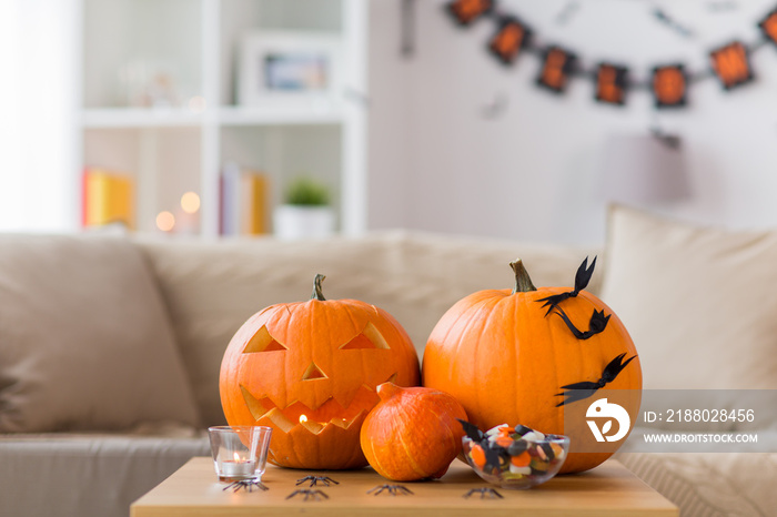 holidays, decoration and party concept - jack-o-lantern or carved pumpkin with halloween decorations