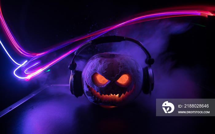 Halloween pumpkin on a dj table with headphones on dark background with copy space. Happy Halloween 