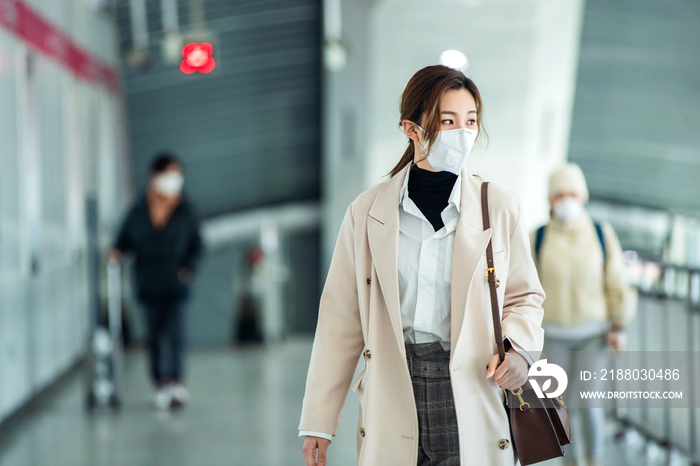 戴口罩的年轻女人走在地铁站里