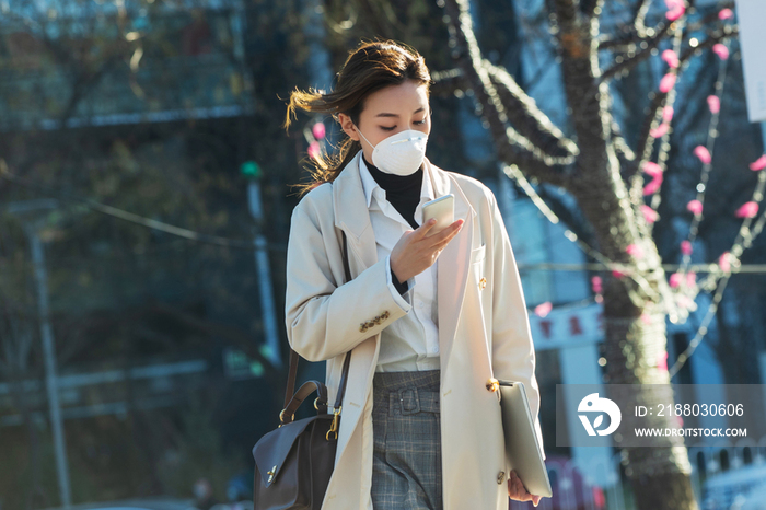 戴口罩的青年女人看手机