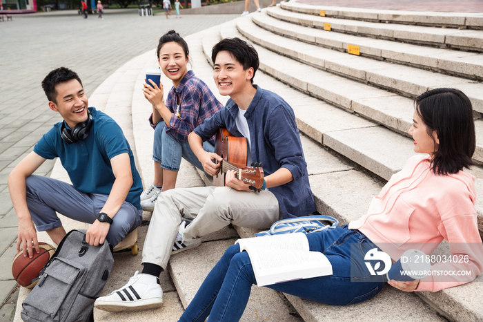 年轻的大学生坐在台阶上弹吉他