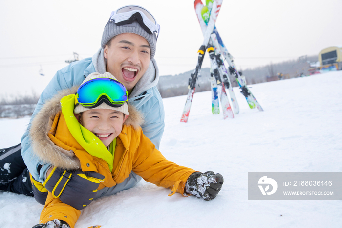 滑雪场内抱在一起打滚的快乐父子