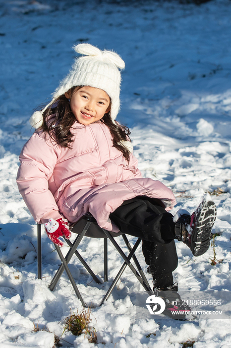 快乐的小女孩坐在雪地上玩耍