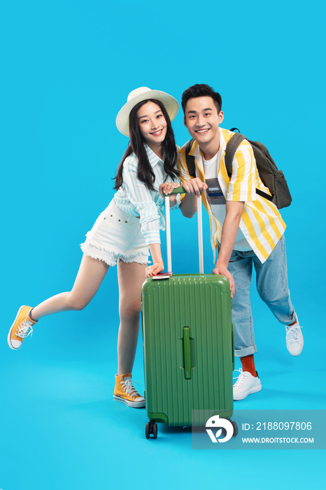 快乐的青年情侣一起推着行李箱去旅游