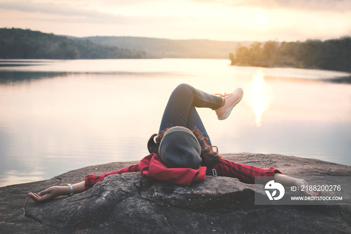 Relaxing moment Asian tourist sleeping on rock waiting for sunset ,enjoying time on holiday concept ,color of vintage tone