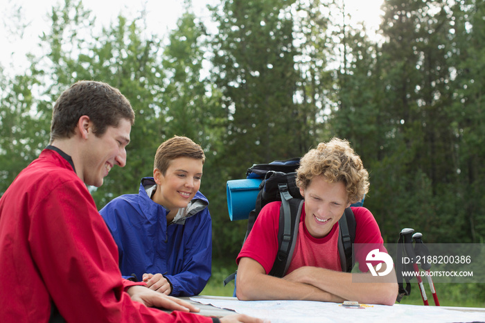 three hikers looking at trail map in the woods