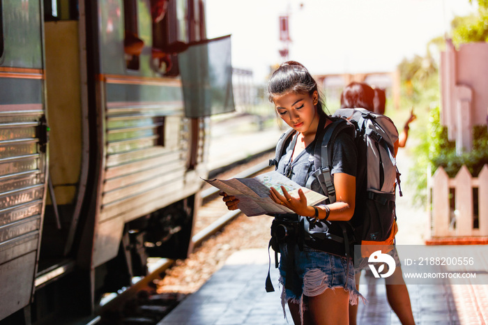 Young asian woman backpacker and traveling looking map for travel at ayutthaya train station background, Ayutthaya Province, Thailand