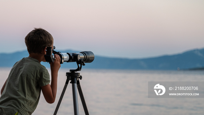 Child exploring the sky looking through a telescope