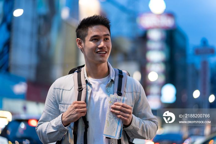 Asian young man backpacker traveler look at map to find destination.