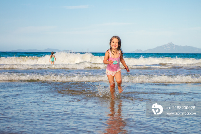 young happy child girl having fun on sand beach, sea background