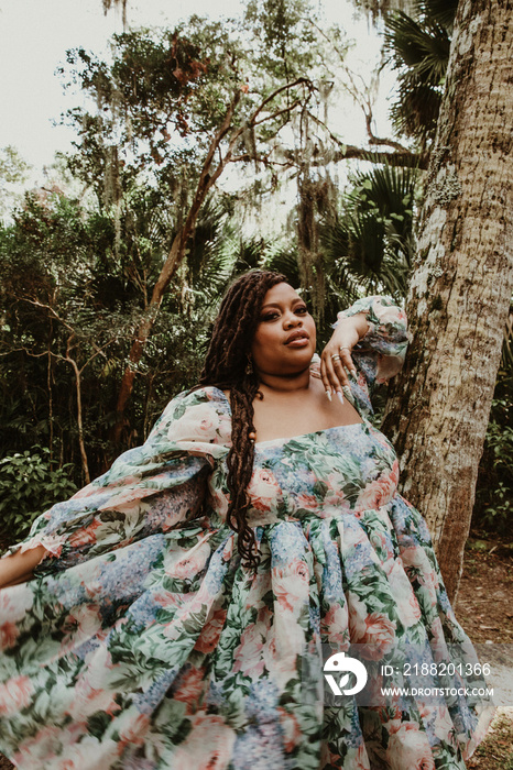 plus size Black woman leans against tree