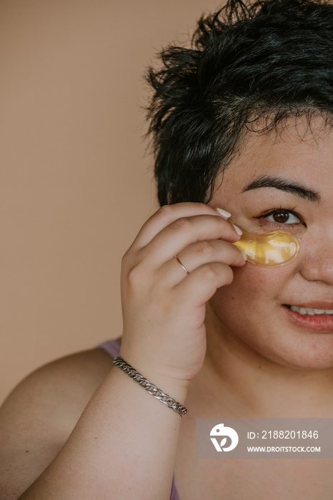 closeup of a plus size filipino woman applying eye pad