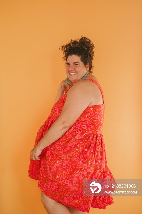 portrait of a plus size person dancing on yellow backdrop