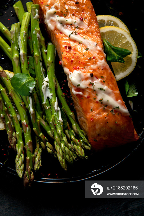 Baked salmon with asparagus on gray background.