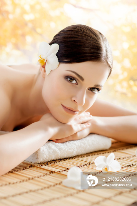 Beautiful, young and healthy woman in spa salon. Massage treatment over yellow autumn background. Traditional medicine and healing concept.