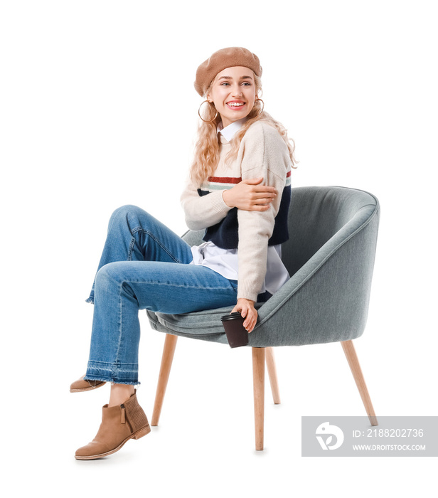 Beautiful young woman in warm clothes sitting on chair against white background