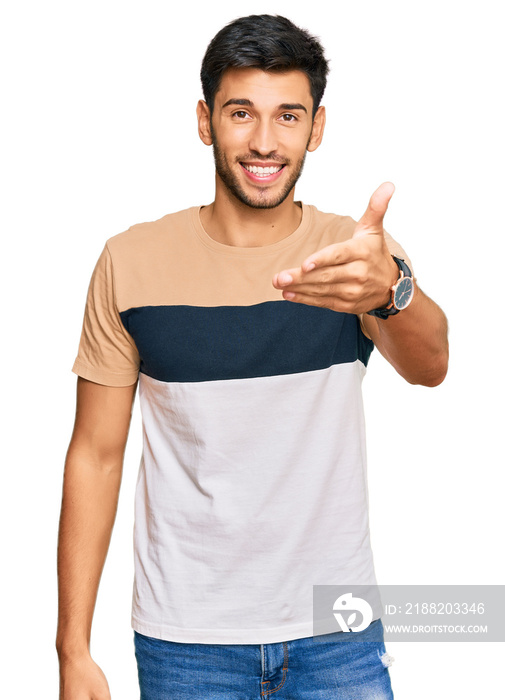 Young handsome man wearing casual clothes smiling friendly offering handshake as greeting and welcoming. successful business.